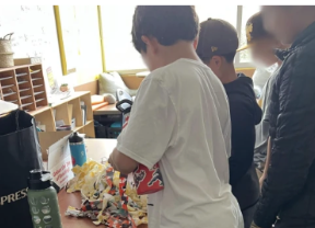 Students sorting through prepared strips of fabric at a classroom table.